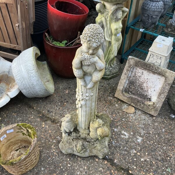 Vintage Fautist statue in a garden setting, a charming stone ornament.