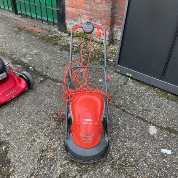 Red Flymo Hover Vac 250 electric lawnmower in a garden setting.