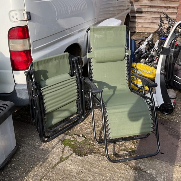Two green folding garden recliners in a garden setting.