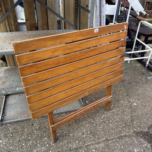 Wooden folding potting table in a garden setting.