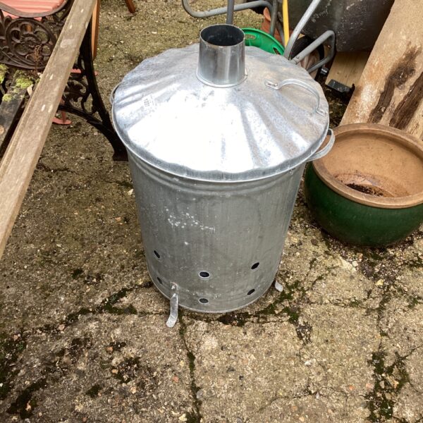 Vintage galvanised log burner in a garden setting.