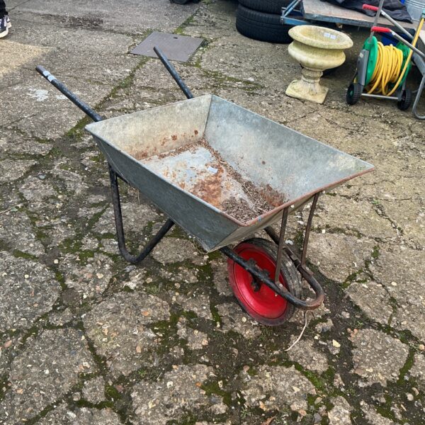 Galvanised wheelbarrow in a garden setting, ready for landscaping work.