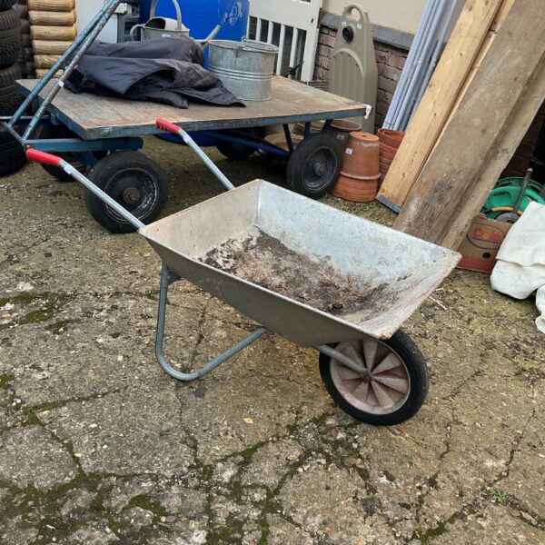 Vintage galvanised wheelbarrow in a garden setting.