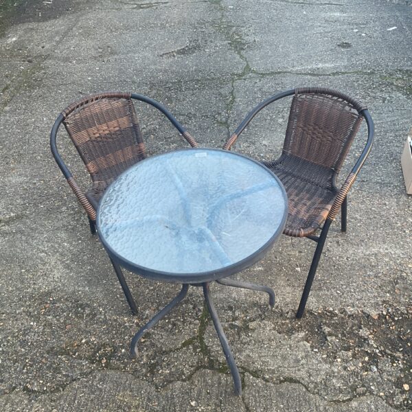 Vintage garden bistro set with rattan chairs and glass table.