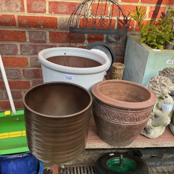 Assortment of three garden plant pots in blue, terracotta, and brown.