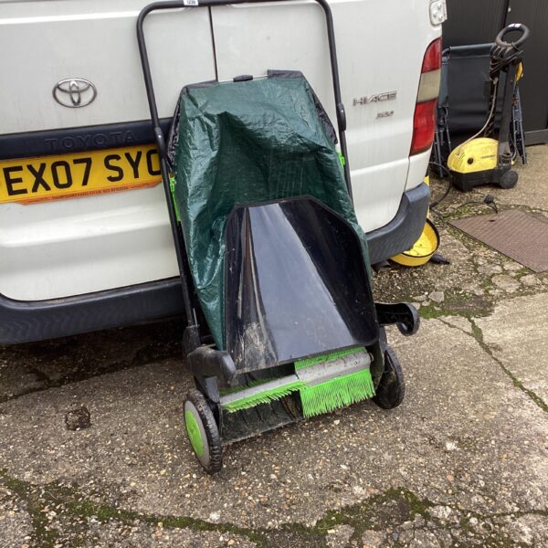 Used garden sweeper with collection bag, ideal for lawn cleaning.