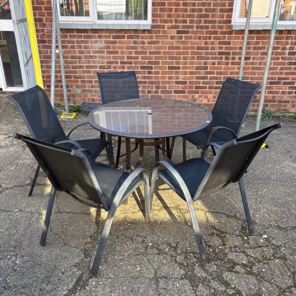 Round garden table and five chairs in a garden setting.