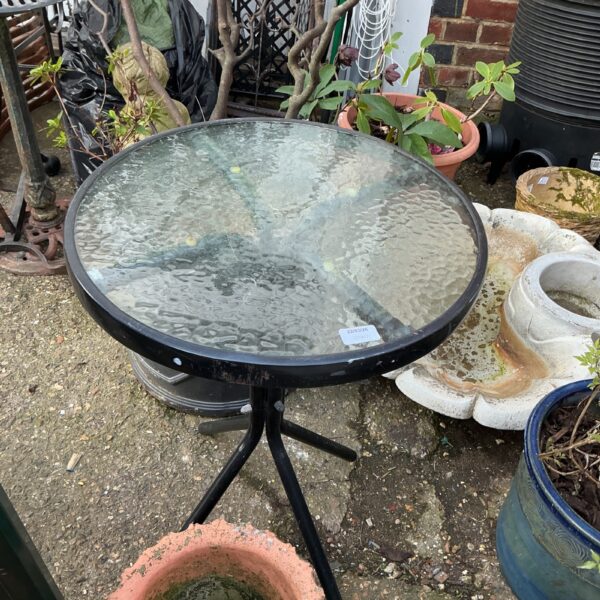Round glass top garden table with metal frame.