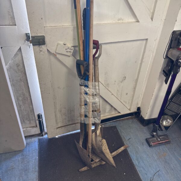 Bundle of used garden tools including a shovel and rake.