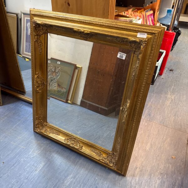 Ornate gilt framed mirror with detailed carving and gold finish.