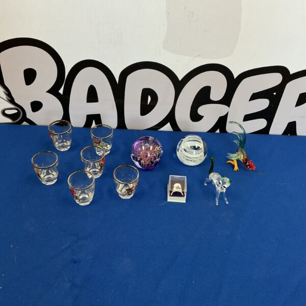 Assorted glassware collection featuring colourful shot glasses and paperweights.