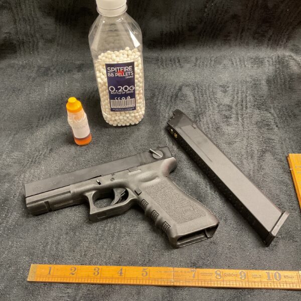 Glock 18c airsoft pistol with BB pellets and oil bottle.