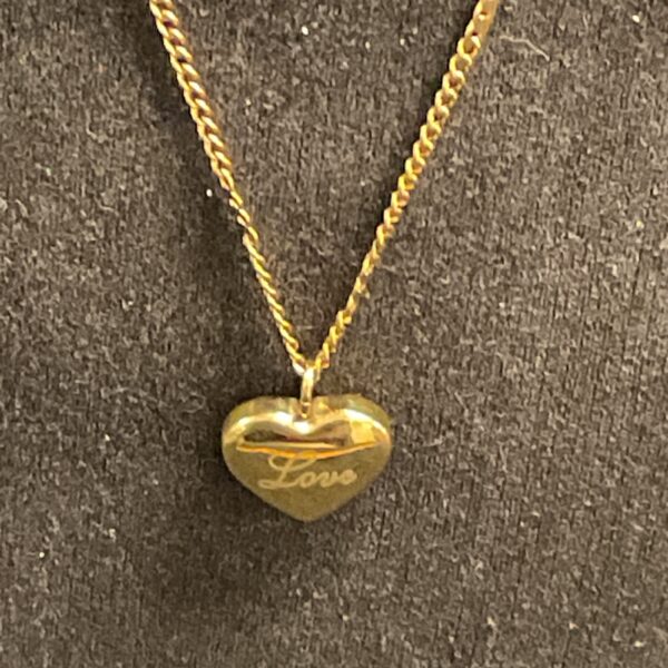 Gold heart pendant necklace with love inscription on chain.
