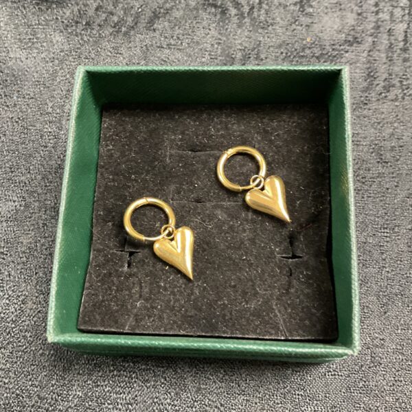 Close-up of gold plated heart earrings on a dark background.