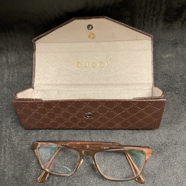 Open Gucci case displaying rose gold reading glasses.