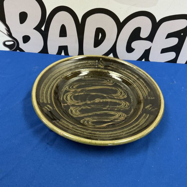 Close-up of a handpainted glazed stoneware plate with dark tones.