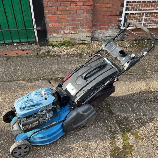 Blue Hyundai petrol lawnmower with broken handle in garden.
