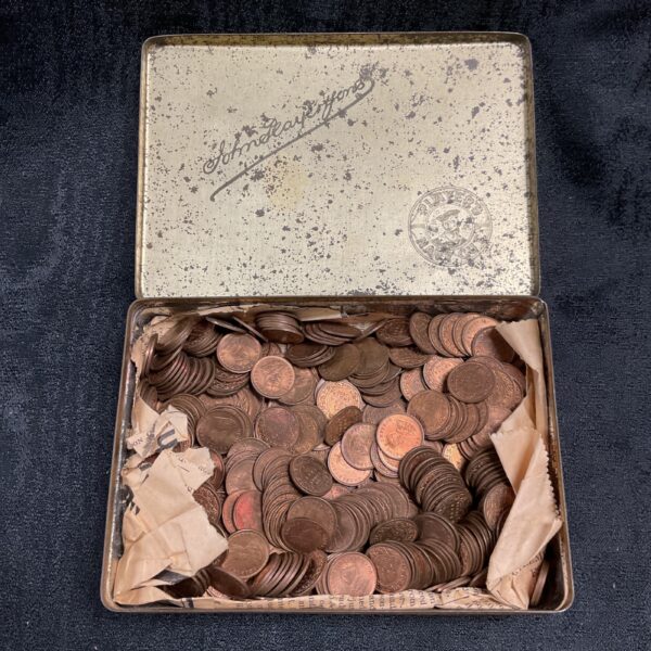 Vintage tin filled with Indian 1/12th Anna coins from the 1930s.