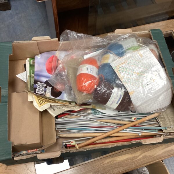 Overview of a colourful knitting supplies lot with wool and needles.