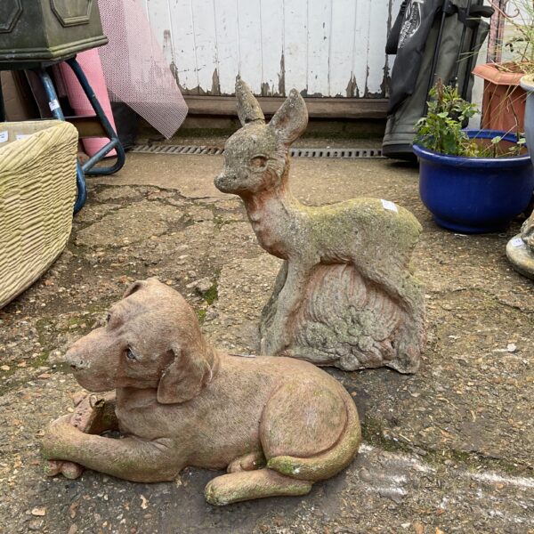 Vintage cast stone Labrador and deer garden ornaments in a garden.