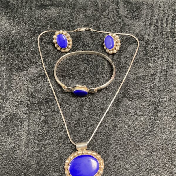 Close-up of lapis lazuli silver jewellery set with necklace, bracelet, and earrings.