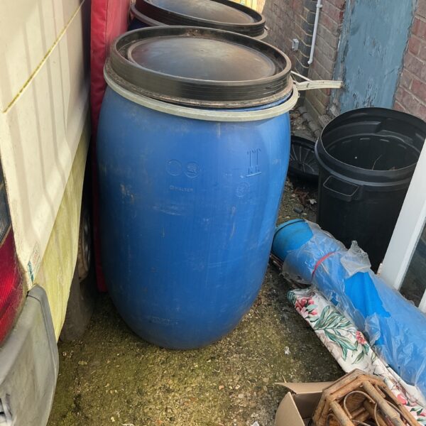 Large blue water butt for rainwater harvesting in a garden setting.