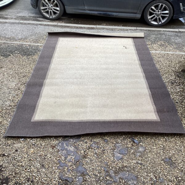 Large hard wearing rug with brown and cream pattern.