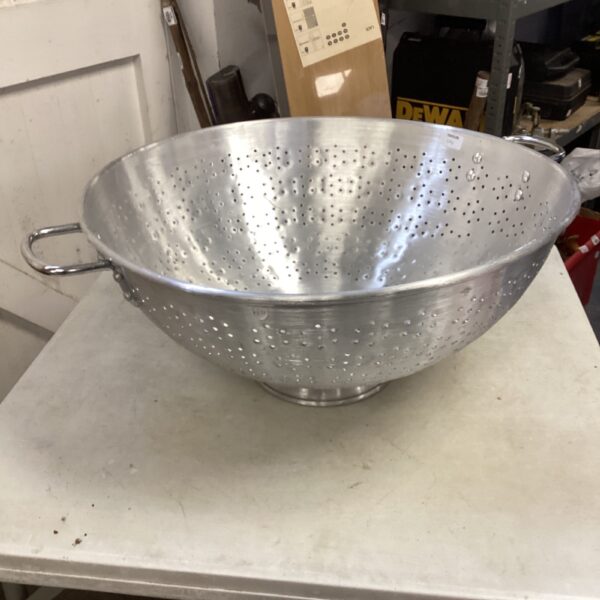 Large stainless steel colander for kitchen use.