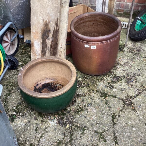 Two large terracotta garden pots in a garden setting.
