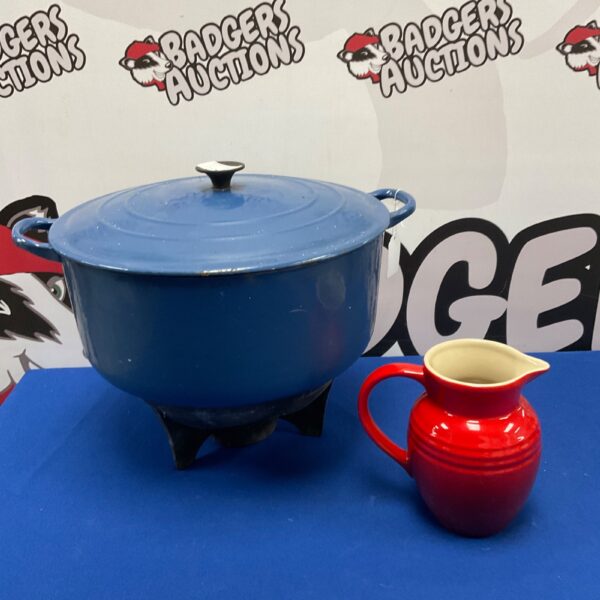 Vintage Le Creuset blue cooking pot and red jug set on display.