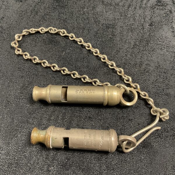 Vintage Leeds Police and Metropolitan Police whistles, collectible memorabilia.
