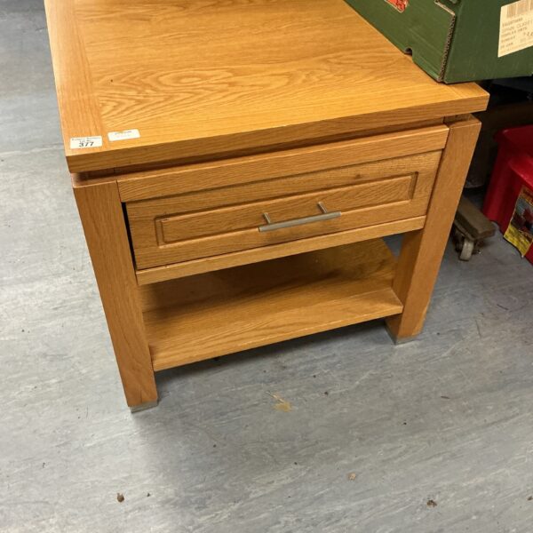 Light oak side unit with a single drawer for storage.