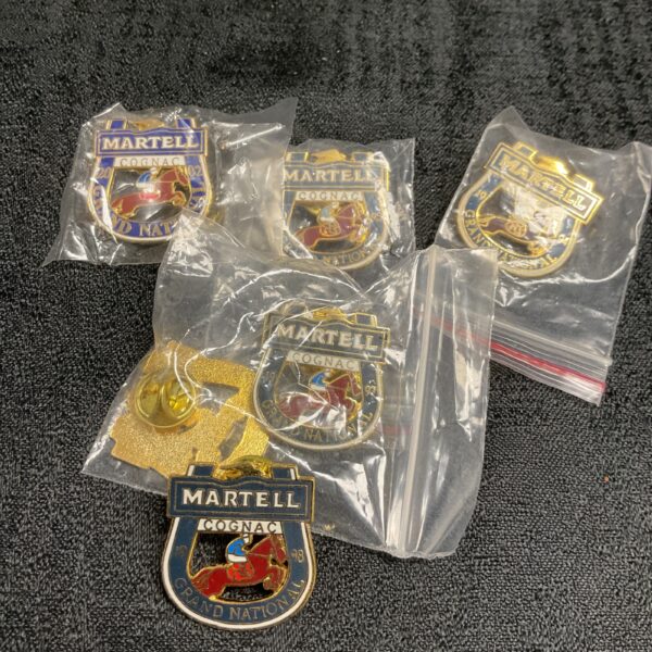 Lot of six Martell Grand National pin badges displayed closely.