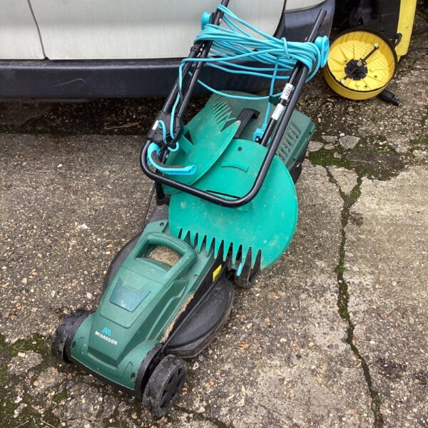 Vintage McGreggor electric lawnmower with accessories in a garden setting.