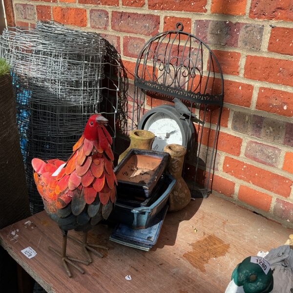 Vibrant red metal garden chicken sculpture in a garden setting.
