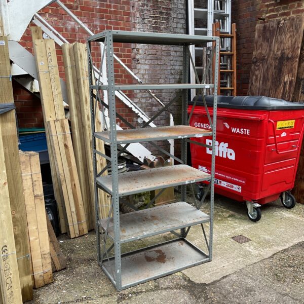 Heavy duty metal shelving unit outdoors with a red bin.