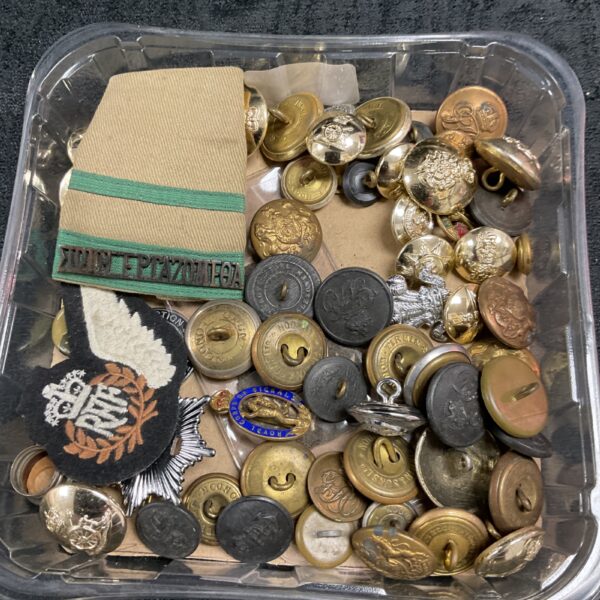 Assorted antique military buttons and badges in a tray.