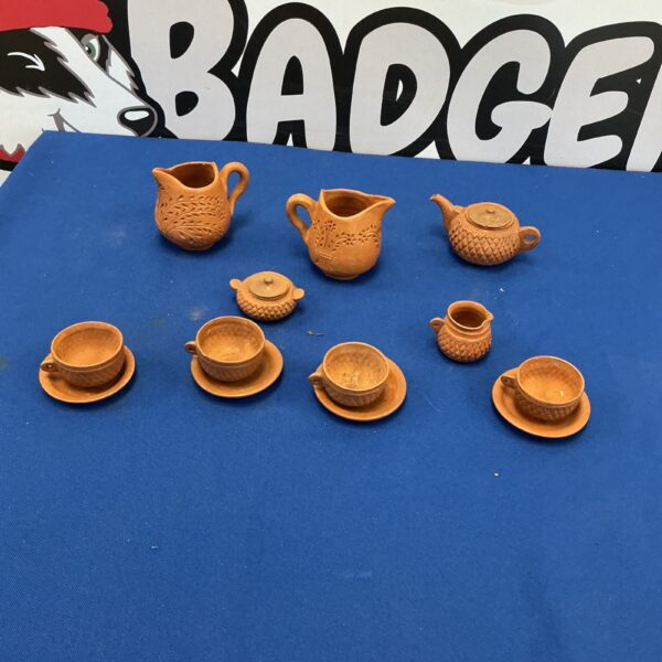 Handmade miniature pottery set with rustic teapot and cups.