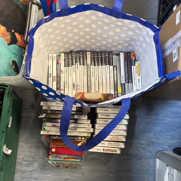 Blue bag filled with a mixed lot of retro video games.