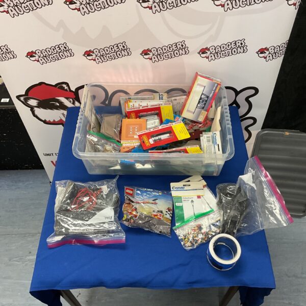 Assorted model train accessories and Lego set in a plastic container.
