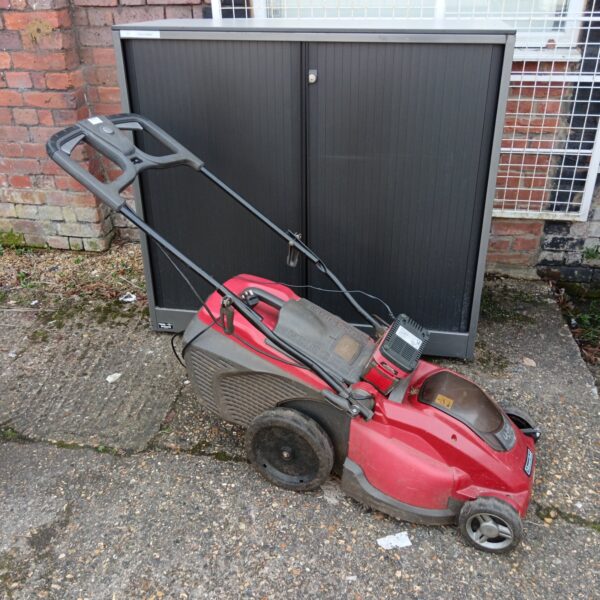 Red Mountfield cordless lawnmower in a garden setting.