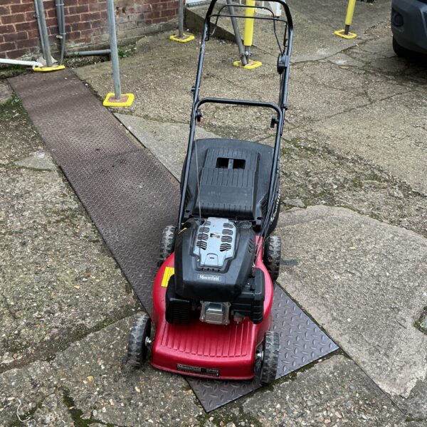 Front view of a red Mountfield petrol lawnmower in a garden.