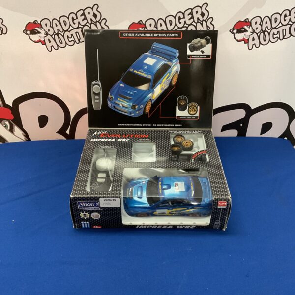 Blue and yellow Nikko Impreza WRC RC car on display.