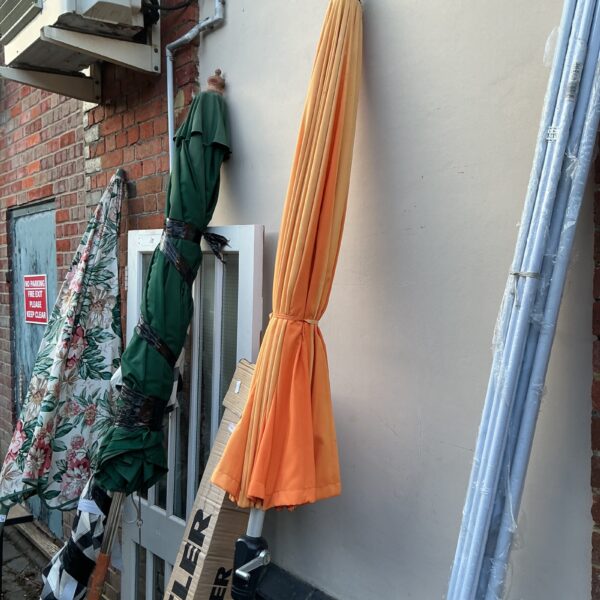 Large orange patio parasol in a garden setting, providing outdoor shade.