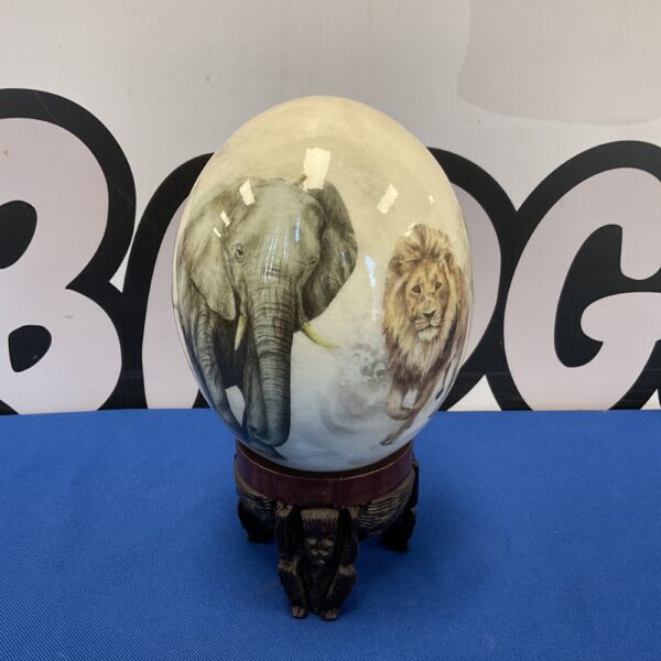 Hand-painted ostrich egg with lion design on ebony base.