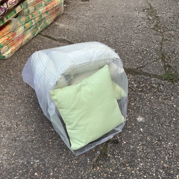 Lot of five patio furniture cushions covered in plastic.