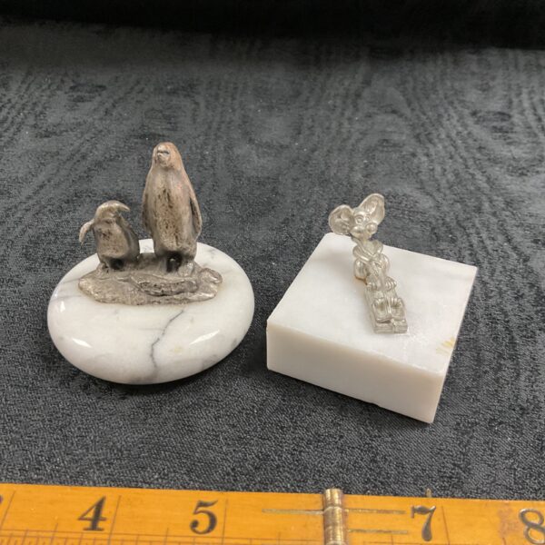 Vintage animal paperweights featuring a penguin and mouse on marble.