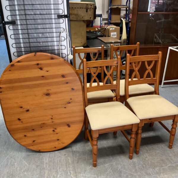 Extending pine dining table with four matching chairs in a kitchen setting.