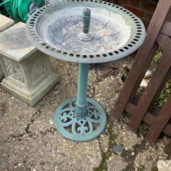 Colourful plastic birdbath in a garden setting.