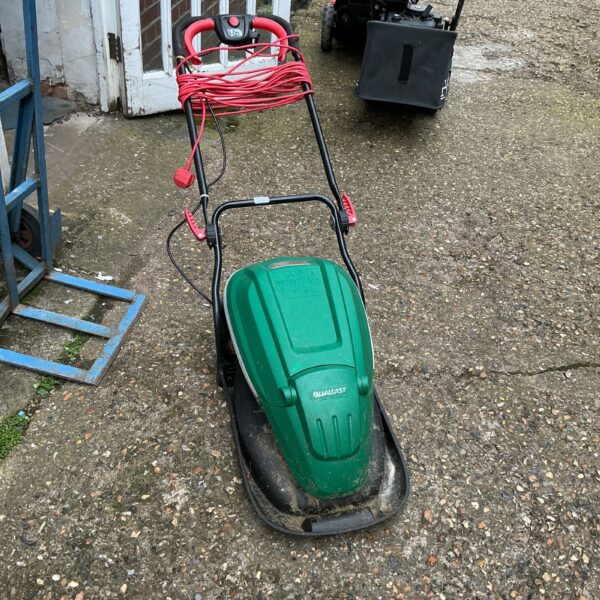 Green Qualcast electric lawnmower in a garden setting.